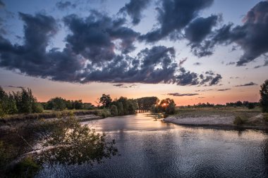 Nehrin üzerinde gün batımı. Batan güneş ve ağır bulutlar.