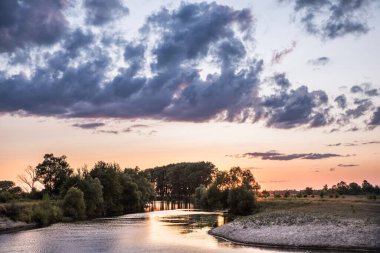Nehrin üzerinde gün batımı. Batan güneş ve ağır bulutlar.