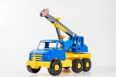 Plastik araba. Oyuncak modeli beyaz arka planda izole edilmiş. Yükünü kaldırmak için ok taşıyan sarı-mavi bir vinç..
