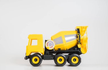 Plastik araba. Oyuncak modeli beyaz arka planda izole edilmiş. Bina betonu taşımak için sarı kamyon.