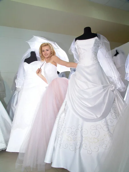 The girl in the salon of wedding dresses. Bride with a white umbrella.