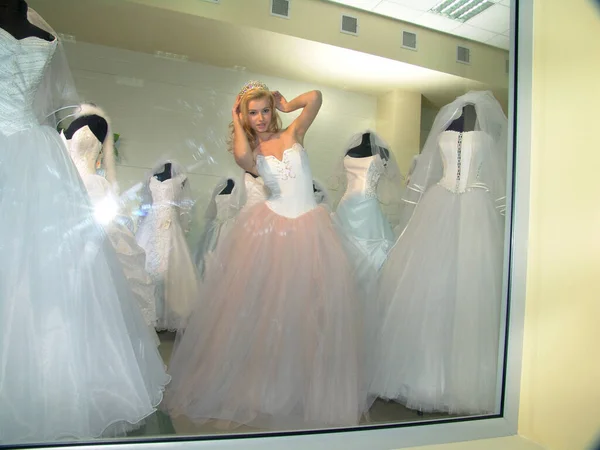 The girl in the salon of wedding dresses. Shop window.