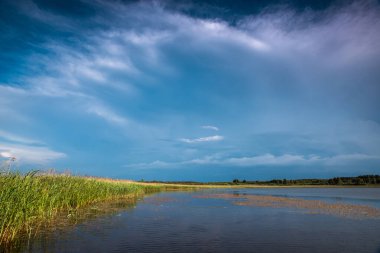 Gölün üzerinde gök gürültülü bulutlar. Sudaki gökyüzünün yansıması..