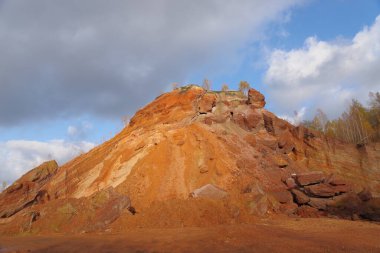 Mavi gökyüzüne karşı ağaçlarla kaplı kırmızı tepeler.