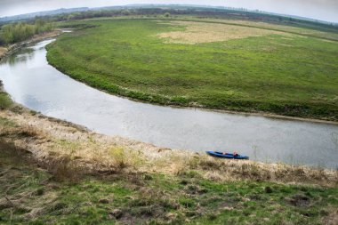 Nehir ve çayır manzarası. İskelede kano..