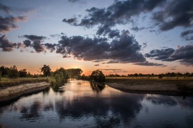 Nehrin üzerinde gün batımı. Batan güneş ve ağır bulutlar.