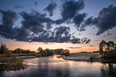 Nehrin üzerinde gün batımı. Batan güneş ve ağır bulutlar.