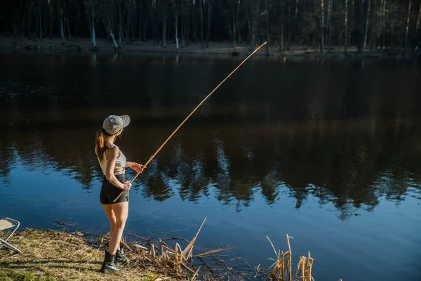 森の湖のほとりに立って釣竿で魚を捕る少女 — ストック写真