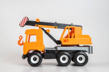 Beyaz arka planda çok renkli plastik çocuk arabaları. Turuncu Vinç.