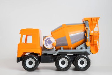Beyaz arka planda çok renkli plastik çocuk arabaları. Turuncu beton kamyon.