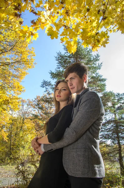 A guy and a girl in an autumn park against a background of yellow foliage. Blurred background. Selective focus.