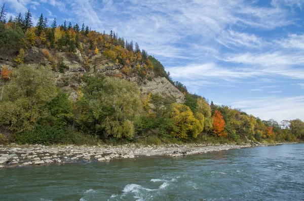 Un río entre las montañas con colorido follaje otoñal y un cielo brillante. — Foto de Stock