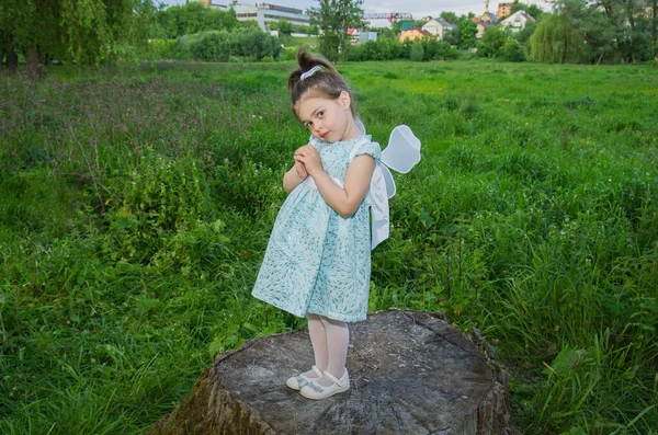 背の高い緑の草の間に大きな木の切り株に蝶の翼を持つ小さなかわいい女の子 選択的フォーカス ぼやけた背景 — ストック写真