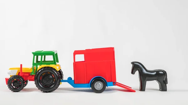 Plastic speelgoed veelkleurige auto 's geïsoleerd op witte achtergrond. Tractor met bestelwagen voor het vervoer van paarden. — Stockfoto