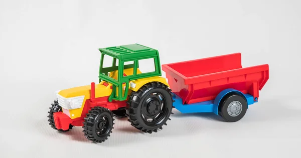 Plastic speelgoed veelkleurige auto 's geïsoleerd op witte achtergrond. Tractor met aanhangwagen. — Stockfoto