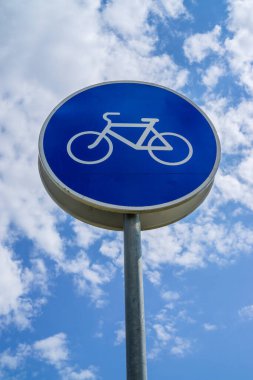 Mavi bulutlu gökyüzünde bisikletlerin hareketi için yol işareti.