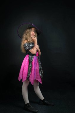 Cadı gibi giyinmiş bir kız ve Cadılar Bayramı için geniş kenarlı bir şapka..