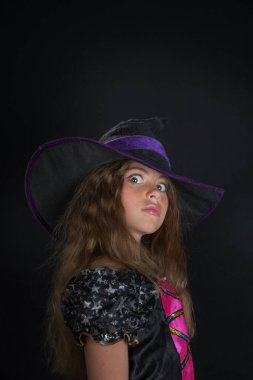 Cadı gibi giyinmiş bir kız ve Cadılar Bayramı için geniş kenarlı bir şapka..