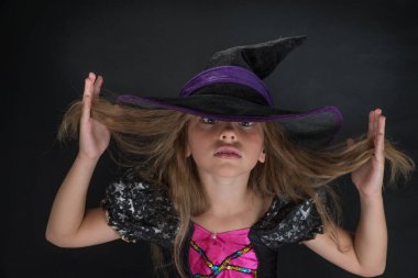 Cadı gibi giyinmiş bir kız ve Cadılar Bayramı için geniş kenarlı bir şapka..