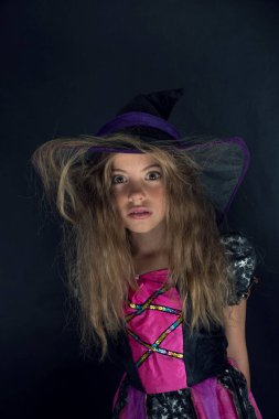 Cadı gibi giyinmiş bir kız ve Cadılar Bayramı için geniş kenarlı bir şapka..