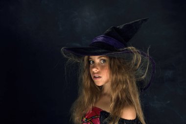 Cadı gibi giyinmiş bir kız ve Cadılar Bayramı için geniş kenarlı bir şapka..
