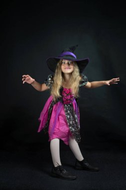 Cadı gibi giyinmiş bir kız ve Cadılar Bayramı için geniş kenarlı bir şapka..