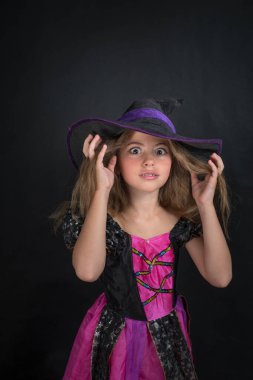 Cadı gibi giyinmiş bir kız ve Cadılar Bayramı için geniş kenarlı bir şapka..