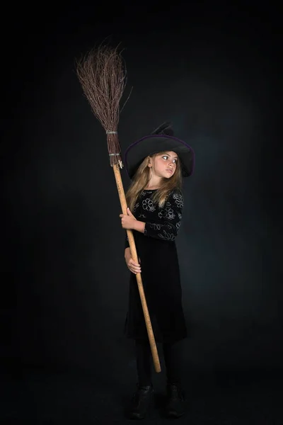 Dívka Tmavém Pozadí Čarodějnickém Kostýmu Klobouku Širokou Krempou Koštětem Halloween — Stock fotografie