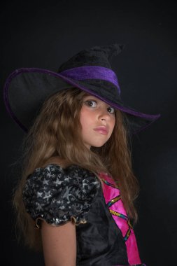 Cadı gibi giyinmiş bir kız ve Cadılar Bayramı için geniş kenarlı bir şapka..