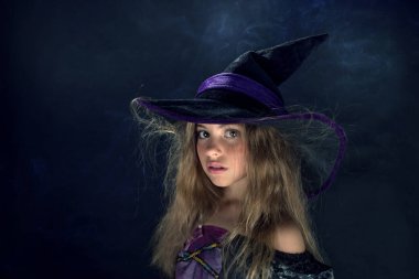 Cadı gibi giyinmiş bir kız ve Cadılar Bayramı için geniş kenarlı bir şapka..