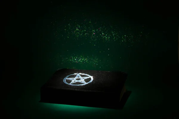 Black magic book on the dark green background. Beautiful occult ritual. Spititual mood.