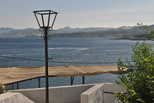 Una lámpara, un arbusto, un dosel y el mar Mediterráneo . — Foto de Stock