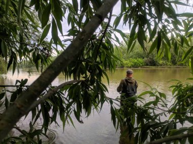 Lastik çizme giymiş deneyimli bir balıkçı Sibirya nehrinde balık tutuyor.