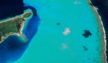 Bora Bora tatil beldesi adasının kıyı manzarası turkuaz su ve kumlu plajlardan kuş bakışı manzaralı.