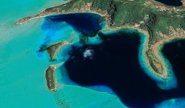 Bora Bora tatil beldesi adasının kıyı manzarası turkuaz su ve kumlu plajlardan kuş bakışı manzaralı.