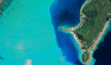 Bora Bora tatil beldesi adasının kıyı manzarası turkuaz su ve kumlu plajlardan kuş bakışı manzaralı.