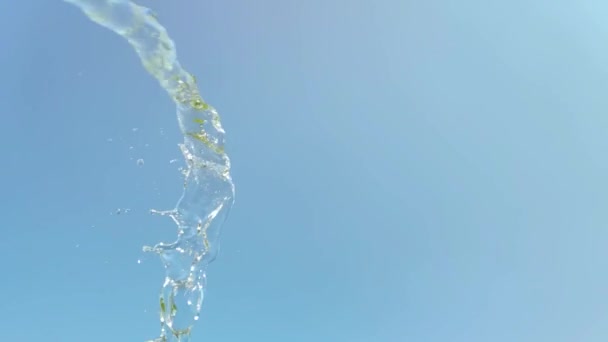 Langzame beweging van een straal water plons op blauwe lucht achtergrond — Stockvideo