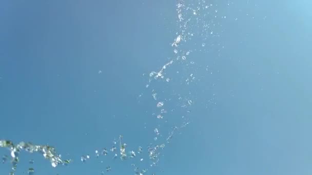 Langzame beweging van een straal water plons op blauwe lucht achtergrond — Stockvideo