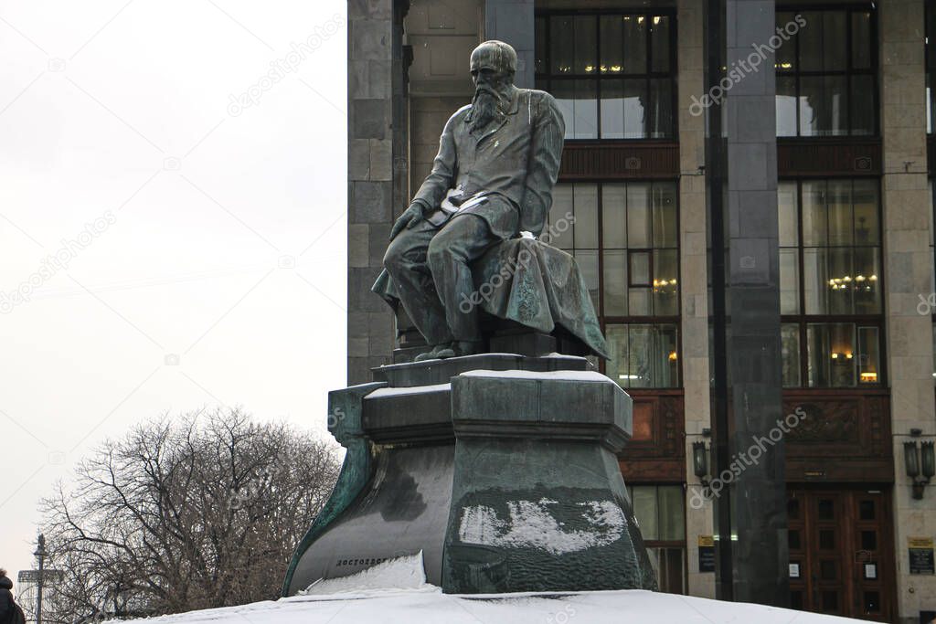 Monument to Fyodor Mikhailovich Dostoevsky near the building of the Russian State Library in Moscow in cloudy weather.