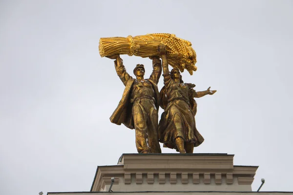 MOSKAU, RUSSLAND-FEBRUAR 2020: Vergoldete Figuren eines Traktorfahrers und eines Kolchosbauern in Nahaufnahme oben auf dem Bogen des Haupteingangs zum WDNH in Moskau — Stockfoto