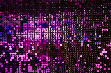 Arka planın parlak dokusu, balık pulu gibi kumaşa dikilmiş yuvarlak mor pullar.