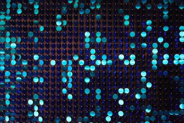 Arka planın parlak dokusu, balık pulu gibi kumaşa dikilmiş yuvarlak mavi pullar.