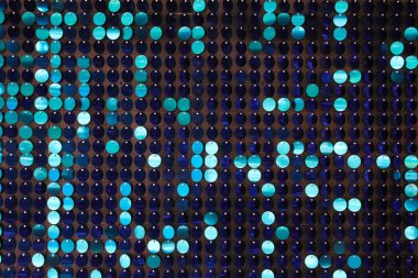 Arka planın parlak dokusu, balık pulu gibi kumaşa dikilmiş yuvarlak mavi pullar.