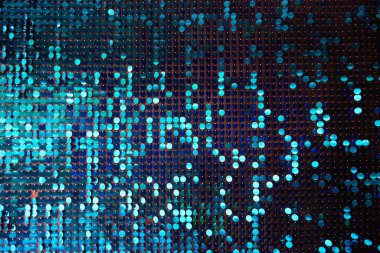 Arka planın parlak dokusu, balık pulu gibi kumaşa dikilmiş yuvarlak mavi pullar.