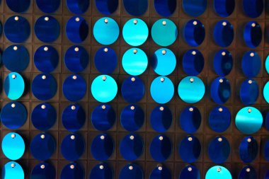 Arka planın parlak dokusu, balık pulu gibi kumaşa dikilmiş yuvarlak mavi pullar.