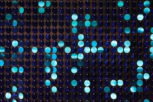 Arka planın parlak dokusu, balık pulu gibi kumaşa dikilmiş yuvarlak mavi pullar.