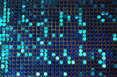 Arka planın parlak dokusu, balık pulu gibi kumaşa dikilmiş yuvarlak mavi pullar.