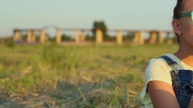 Bir kız gün batımında parkta lezzetli bir karpuz yiyor.