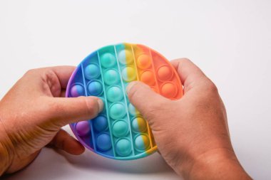 Multi-colored children's toy Pop it in the hands on a white background