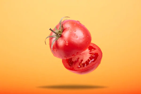 Olgun bir domates turuncu bir arka planda havayı kesiyor. — Stok fotoğraf